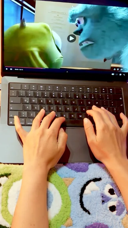 Manos escribiendo en un teclado sobre un tapete de Monsters, Inc. hecho a mano